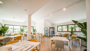 A spacious dining area with tables and chairs, large windows, and potted plants. - Lodge in Rimini Family Village near the beach (Viserba, Rimini)