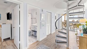 A modern interior with a spiral staircase, a bathroom with a shower, and a dining area with chairs and a table.