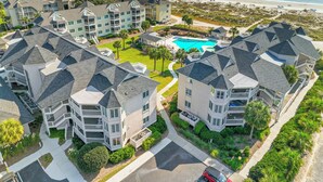 A coastal hotel with multiple buildings, a swimming pool, and a beach view.