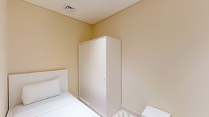 A bedroom with a bed, a wardrobe, and a white wall. - Lux 3 Bed | Private Beach Access, Emaar Beachfront I Sunrise Bay Tower 2 (Emaar Beachfront)