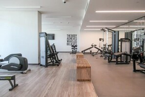 A gym with various exercise equipment, a motivational quote on the wall, and a wooden bench. - Lux 3 Bed | Private Beach Access, Emaar Beachfront I Sunrise Bay Tower 2 (Emaar Beachfront)