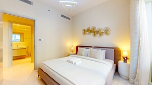 Een hotelkamer met een groot bed, nachtlampjes, een ventilator aan de muur en een badkamer die door een open deur zichtbaar is.