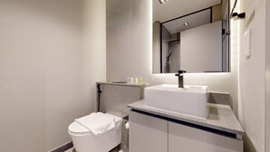Ein modernes Badezimmer mit einer weißen Toilette, einem Waschbecken mit Spiegel darüber und einem Handtuch an der Wand.