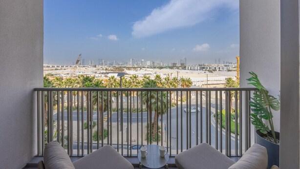 Ein Balkon mit Blick auf eine Stadtlandschaft, einschließlich Gebäude und Palmen.
