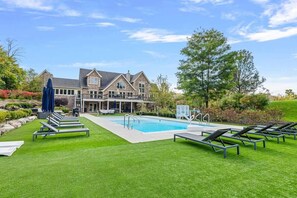 Ein Poolbereich mit Liegestühlen und einem Haus im Hintergrund.