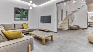 A modern living room with a sofa, coffee table, and a staircase leading to another level.