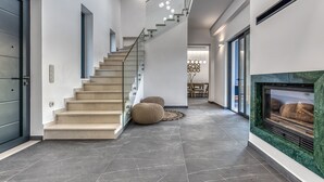 A modern interior with a staircase, a fireplace, and a dining area.