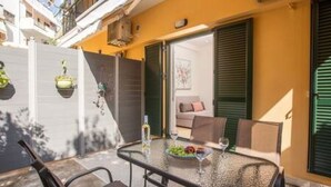 A glass-top table with chairs, a sofa, and a door leading to an interior room. - Bethy's #1|Double BR Apt (Corfu)