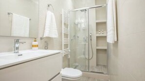 A modern bathroom with a glass-enclosed shower, a white sink, and a toilet.