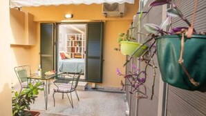 A small outdoor seating area with a table and chairs, a potted plant, and a hanging plant basket.