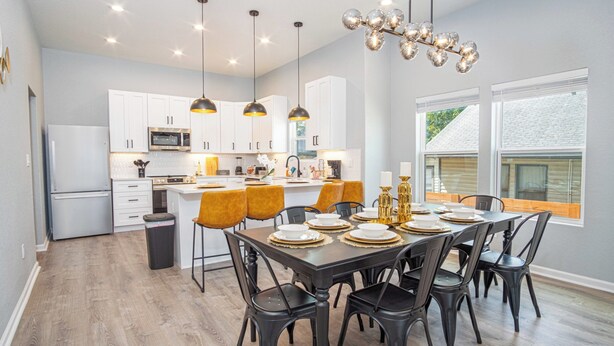 Une cuisine moderne avec des meubles blancs, un îlot central et des luminaires suspendus.