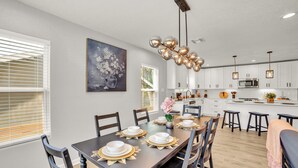 A modern kitchen with white cabinets, a central island, and pendant lighting.