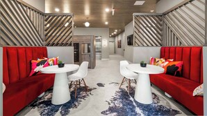 A modern hotel lobby with red upholstered seating, white round tables, and a wooden ceiling. - Luxury 2BR Apt + Work-From-Home Space (New Haven)