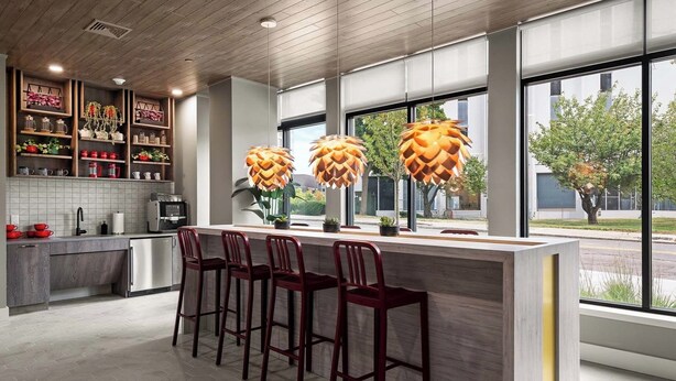A modern kitchen with a bar area, large windows, and a view of the street. - Luxury 2BR Apt + Work-From-Home Space (New Haven)