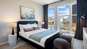 Une chambre d’hôtel moderne, dotée d’un grand lit, offrant une vue sur la ville et permettant d’admirer le paysage urbain à travers la fenêtre.
