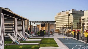 Une terrasse sur le toit avec des chaises longues, un espace barbecue et un terrain de jeu de palet.