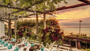 An outdoor dining area with white tables, teal glassware, and floral centerpieces against a sunset backdrop. - Villa Sogno by My Villa Collection (Sant'Agnello di Sorrento)