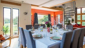 A dining area with a table set for six, large windows, and a spiral staircase.