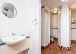A bathroom with a white sink, a round mirror, and a towel ring.