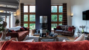 A spacious living room with a fireplace, large windows, and comfortable seating.