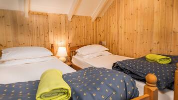 Una habitación de madera con dos camas, cada una con una almohada y una lámpara.
