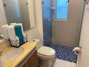 Bathroom features a toilet, sink, and mirror, with a towel rack and blue mosaic tiles.