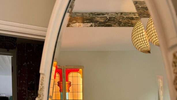 Une chambre de style vintage avec un lit, une porte en arc décorative et un vitrail.