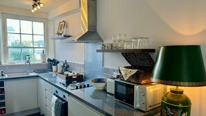 Une cuisine moderne dotée d’un four encastré, d’un four à micro-ondes et d’une lampe décorative de couleur verte.