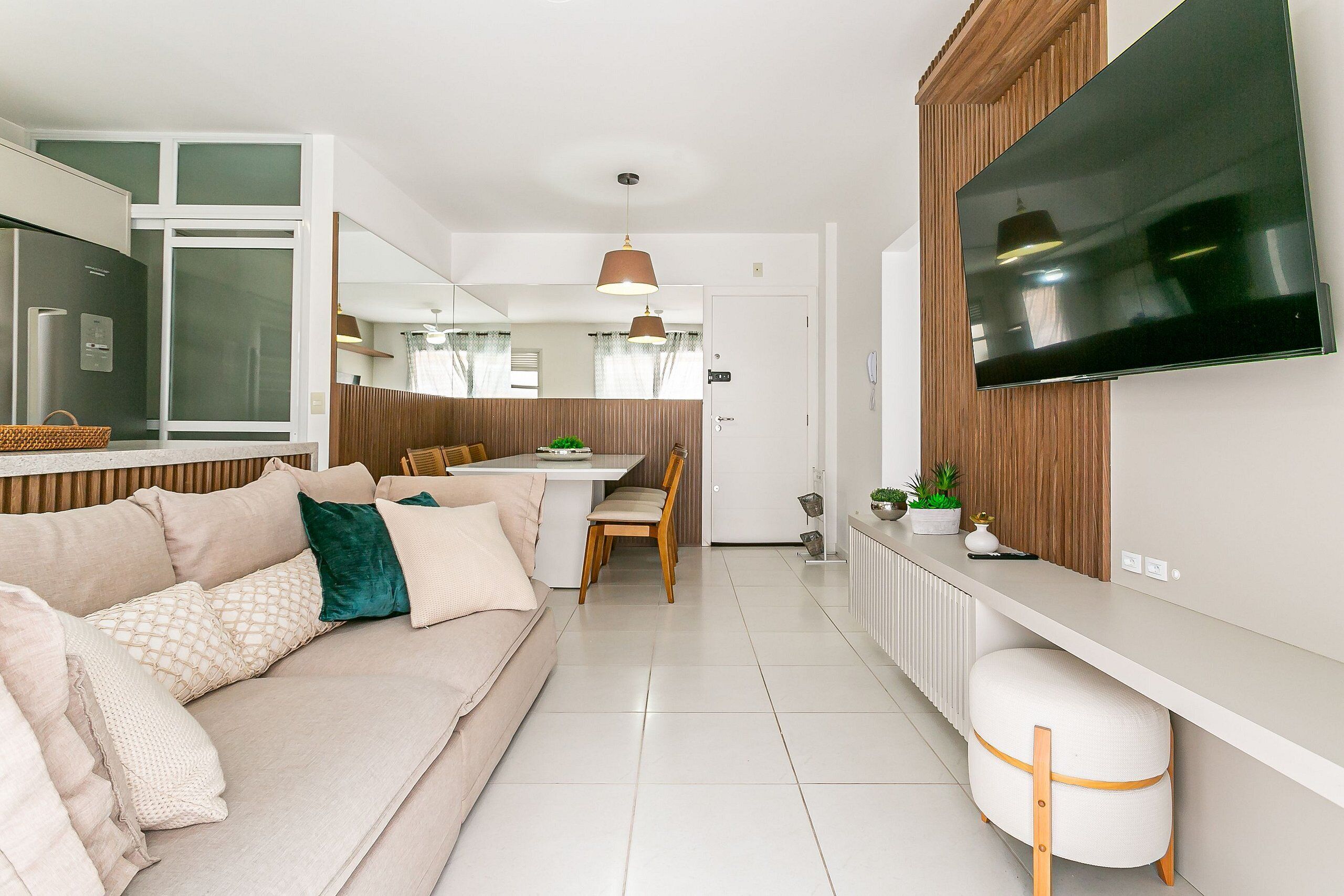 A modern kitchen with a flat-screen TV, a dining area with a table and chairs, and a living space with a sofa and ottoman.