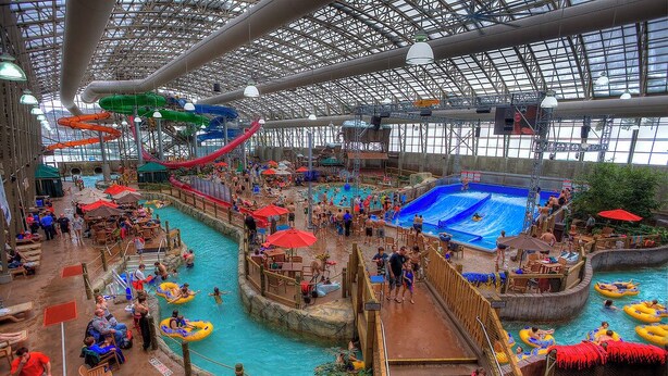 Parque acuático interior con múltiples piscinas, toboganes y zonas de descanso.
