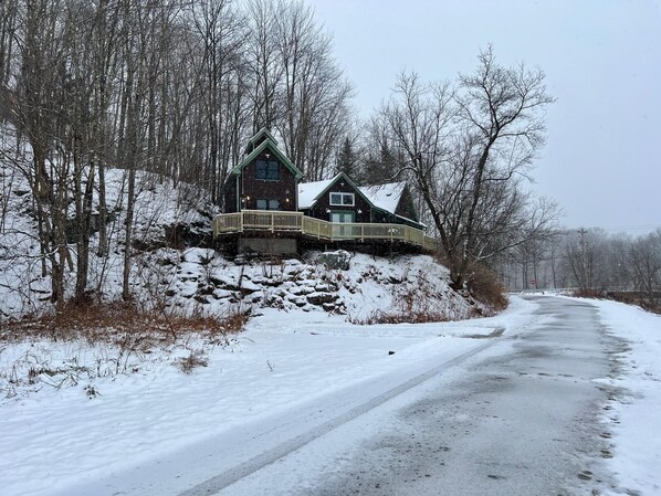 Una casa de dos pisos con un balcón de madera y un paisaje nevado.