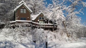 Una casa de dos pisos con un porche y un paisaje cubierto de nieve.