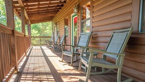 A covered porch with wooden railings and rocking chairs.