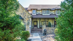 Une maison en pierre avec une façade en pierre, une terrasse en bois et un chemin en pierre menant à l’entrée.