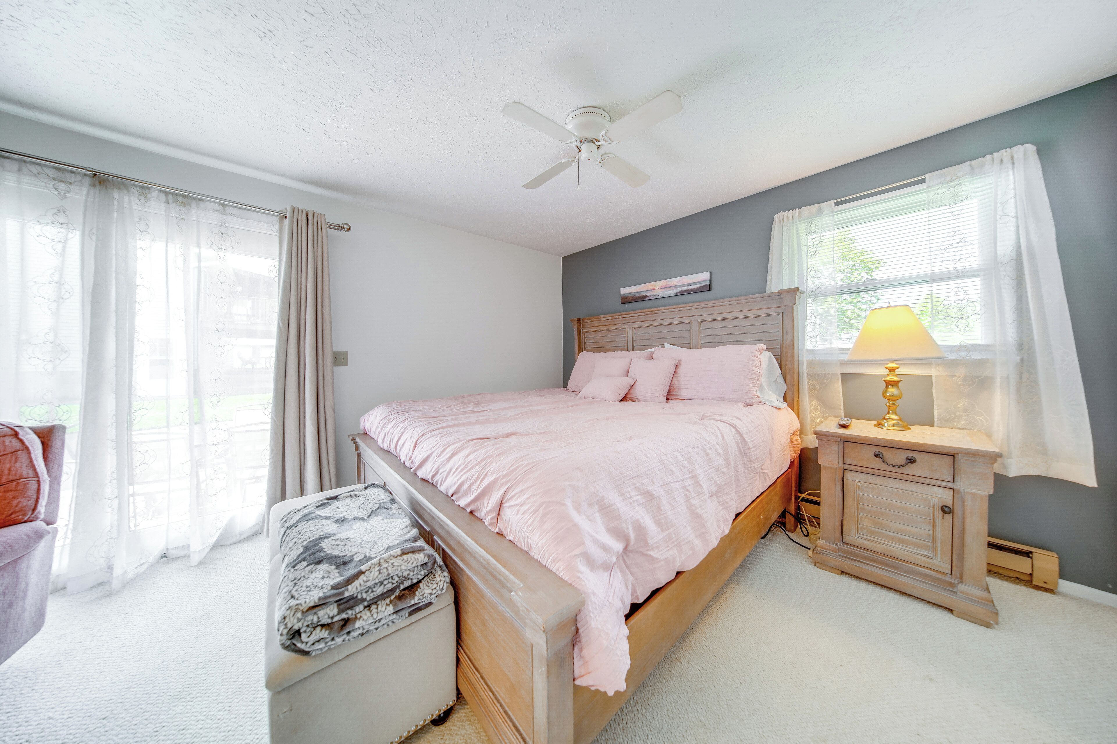 Une chambre à coucher avec un lit, une table de chevet, une chaise et une fenêtre avec des rideaux.