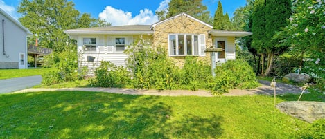 A two-story house with a stone facade, a front porch, and a well-maintained lawn.