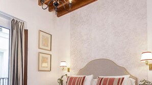 A bedroom with a large bed, wooden ceiling beams, and two wall-mounted lamps. - Genteel Home Teodosio II (Seville)