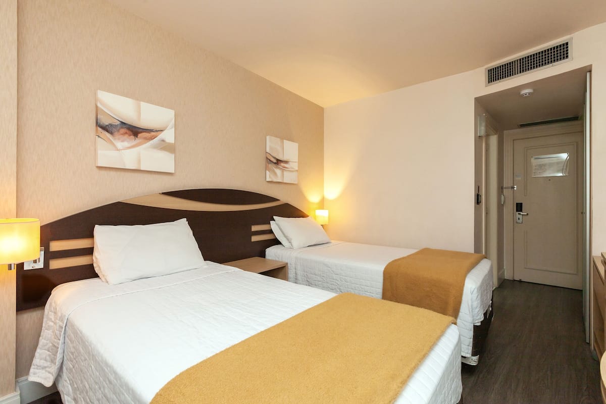 Una habitación de hotel con dos camas, cabeceras, decoración en la pared y una puerta.