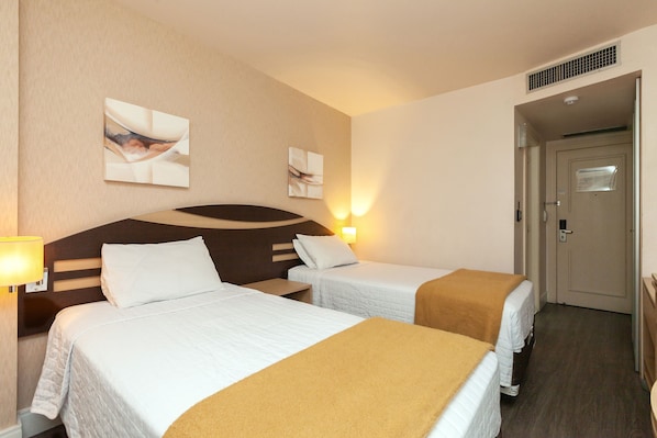 A hotel room with two beds, a headboard, wall art, and a door. - TRI HOTEL VITTORIA BENTO (Bento Gonçalves)