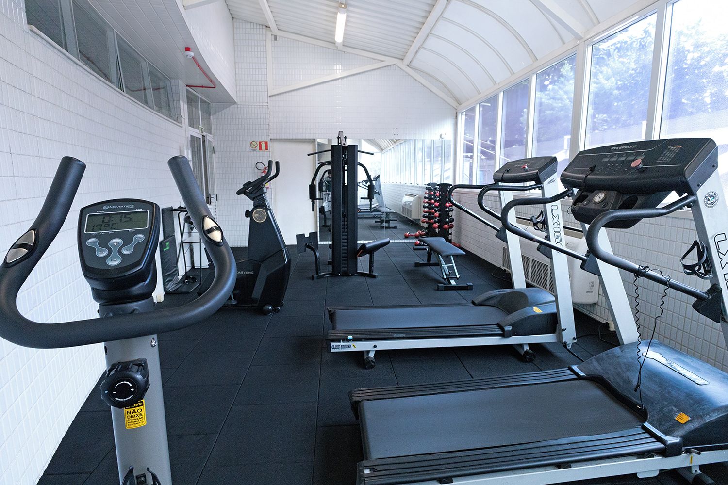 Un gimnasio con cintas de correr, elípticas y equipo de pesas.