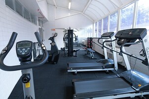 Un gimnasio con cintas de correr, elípticas y equipo de pesas.