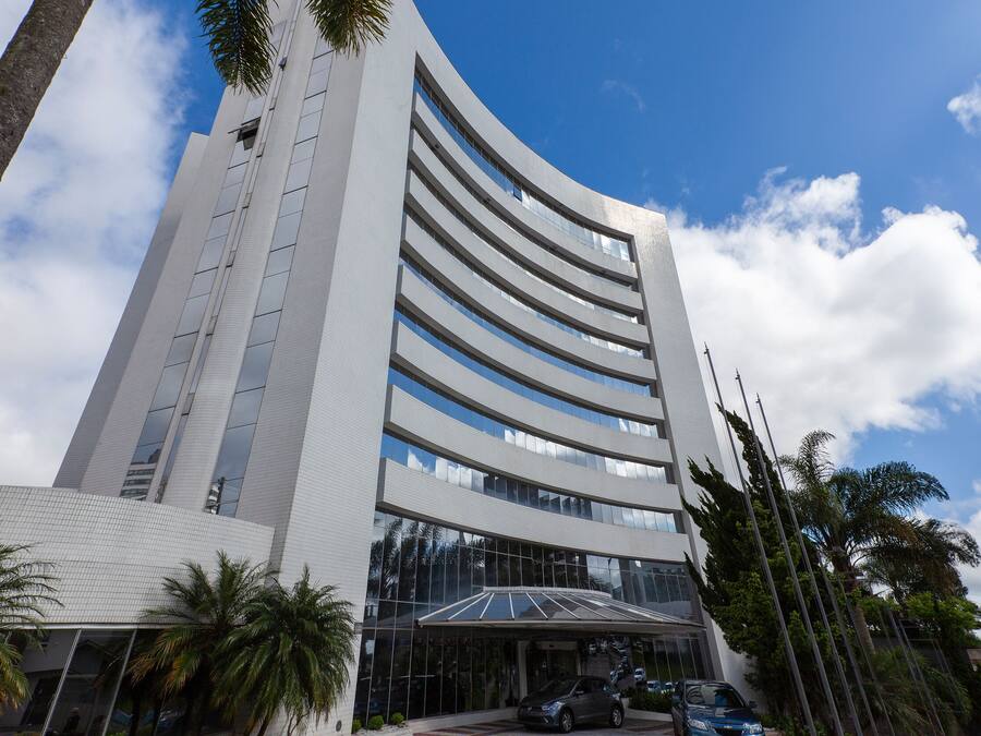 Un edificio moderno con fachada curva, ventanas amplias y un área de entrada cubierta.
