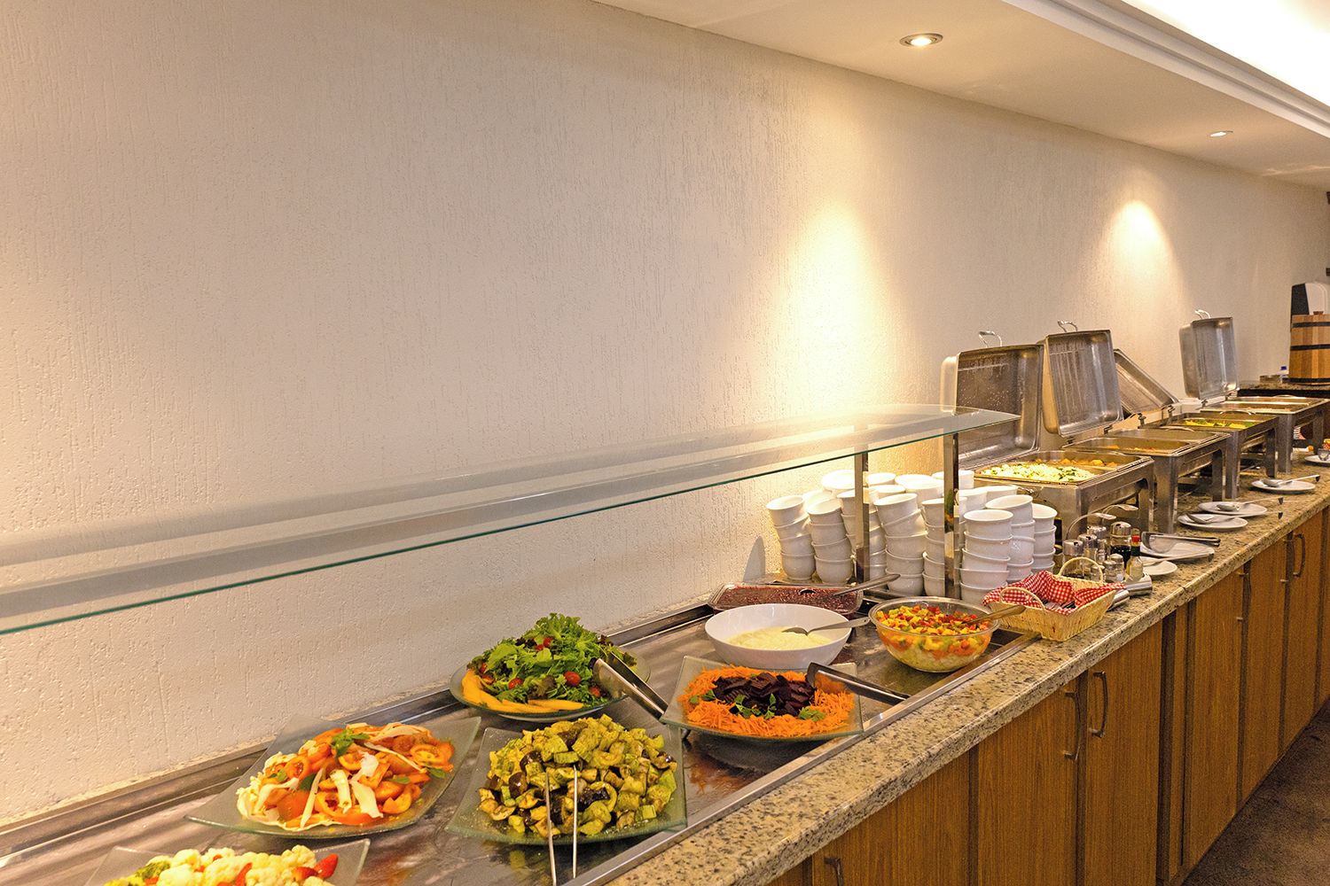 A buffet with various food options, including salads, fruits, and desserts.