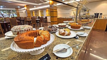 A buffet area with various baked goods displayed on plates and a sign indicating a special offer.