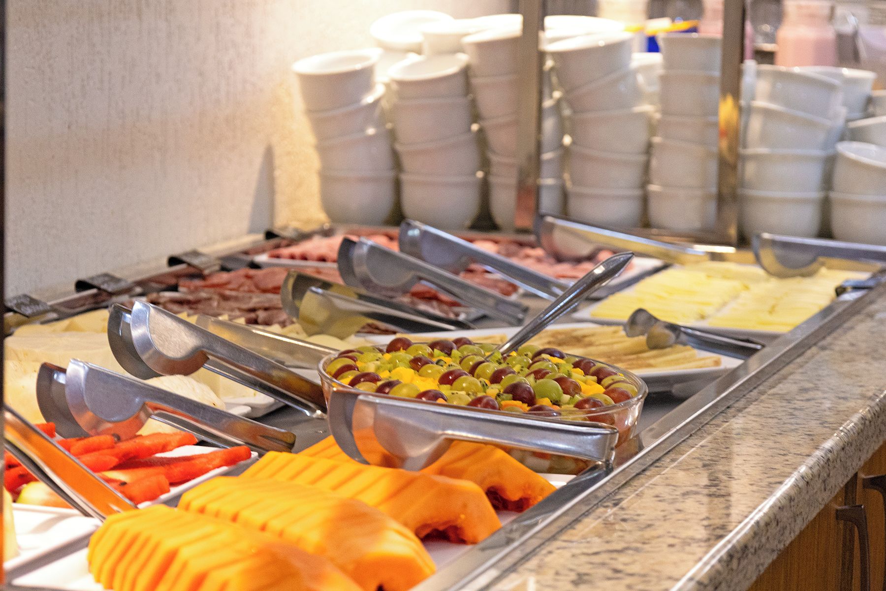 Un bufé con diversos alimentos y utensilios de servicio.