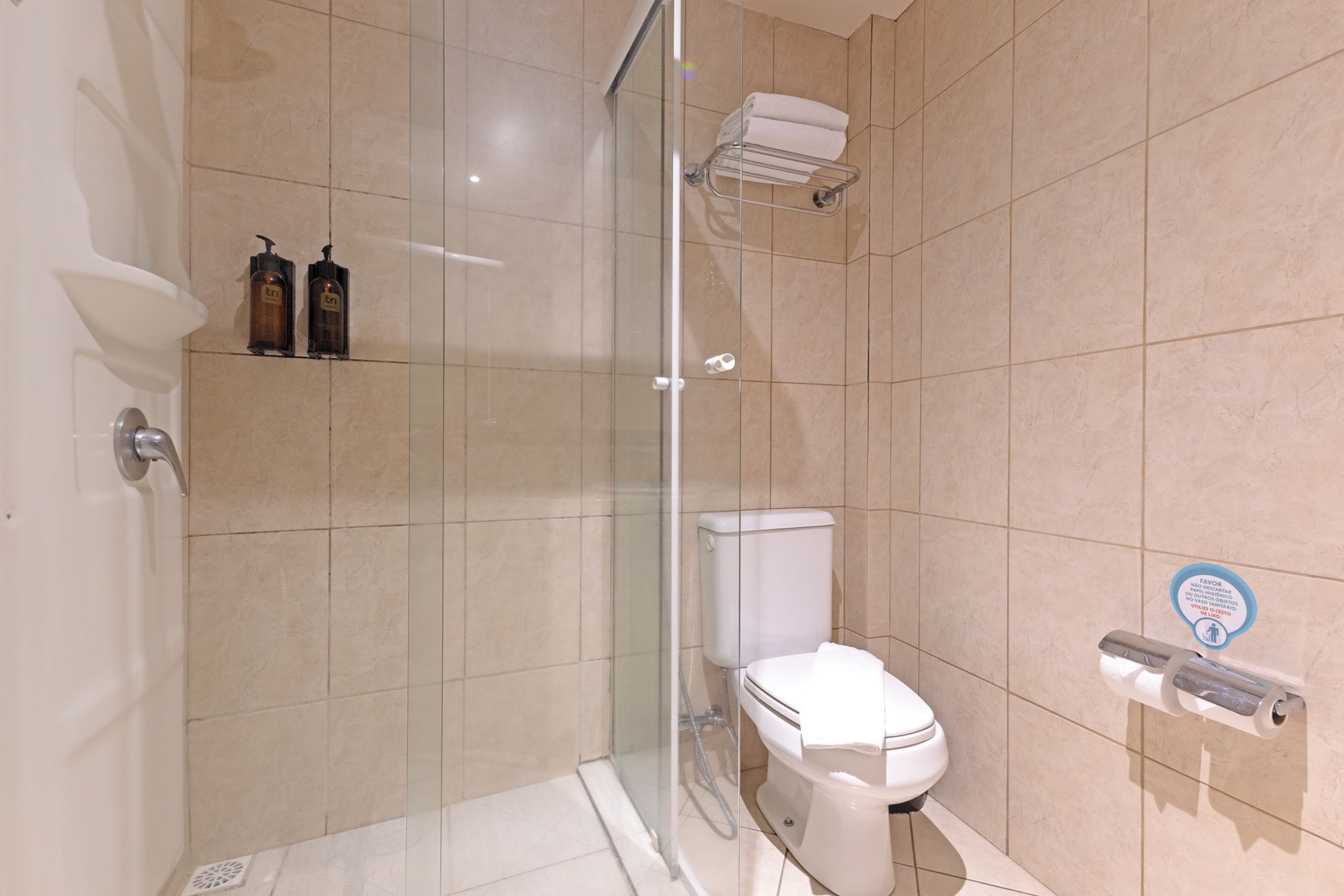 Une salle de bain moderne avec une douche à parois de verre, des toilettes et un porte-serviettes.