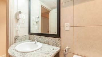 Et badeværelse med vask i granit, et spejl, en hårtørrer og et toilet.