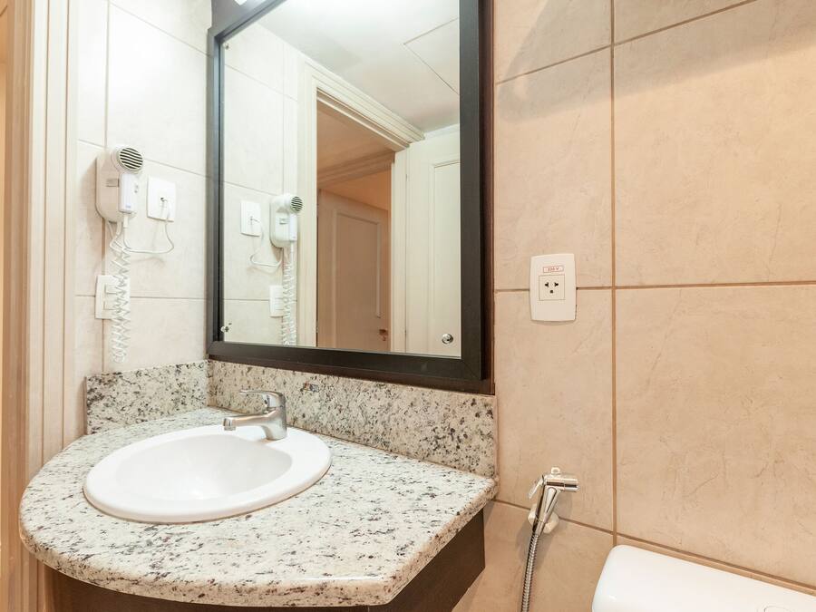 Et badeværelse med vask i granit, et spejl, en hårtørrer og et toilet.