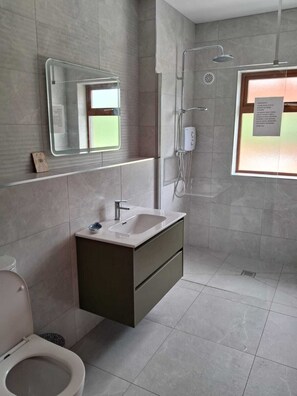 A modern bathroom with a toilet, sink, and shower.
