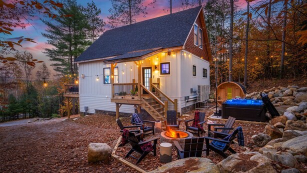 A cabin with a deck, a hot tub, and outdoor seating. - Luxe Retreat: Sleeps 16, Hot Tub, Sauna & Movie Room (Bethel)